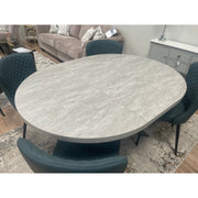 The Rimini Round Extending Table with a light gray stone-effect top is paired with four dark upholstered chairs, creating a space-saving setup on a patterned rug in a contemporary living room.