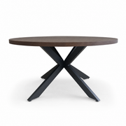 The Olson 1.5 Round Dining Table features a dark brown top and black metal crossed legs, seating six guests. Its striking design stands out beautifully against a white background.