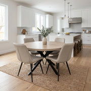 Modern kitchen and dining area featuring the Dalton Table with 4 Lyra Chairs, a vase with greenery, a woven rug, white cabinets, a kitchen island with stools, and plenty of natural light.
