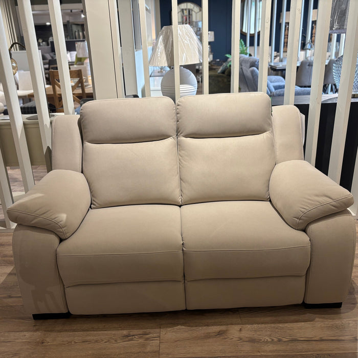 The Lorenzo Electric Recliner Sofa, featuring plush washable cushions and wide armrests, is showcased on a wooden floor in a bright living room with decorative accents and additional furniture in the background.