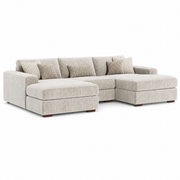 The Henley Sofa is a light beige modular sofa featuring a chaise lounge, low wooden legs, and several matching throw pillows crafted from soft chenille fabric, displayed against a plain white background.