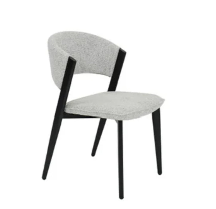 The Titan Dining Chair features a curved backrest and seat upholstered in light gray stone fabric, complemented by black angled legs and arm supports, all set against a plain white background.