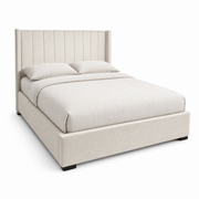 The Kildare Bedframe is a modern beige velvet bed with a tall winged headboard featuring vertical lined stitching, shown neatly made with light beige bedding and two pillows against a white background.