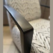 Close-up of the Falcon Accent Chair, showcasing its contemporary design with black wooden armrests and light-patterned upholstery, while identical Falcon Accent Chairs appear softly blurred in the background.