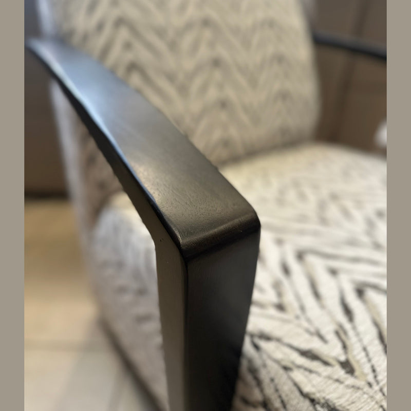 Close-up of the Falcon Accent Chair, showcasing its contemporary design with black wooden armrests and light-patterned upholstery, while identical Falcon Accent Chairs appear softly blurred in the background.