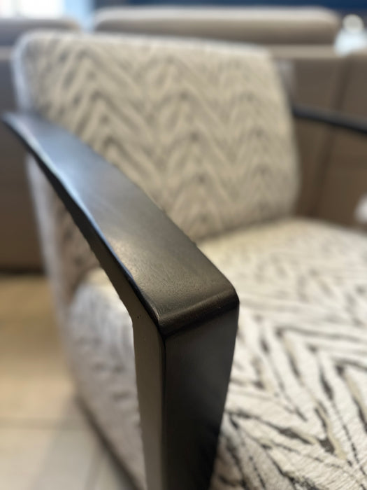 Close-up of the Falcon Accent Chair, showcasing its contemporary design with black wooden armrests and light-patterned upholstery, while identical Falcon Accent Chairs appear softly blurred in the background.