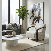 Modern living room with large windows, a gray sofa, patterned armchair, marble coffee table, potted plant, abstract wall art, and a neutral rug on a polished floor. The space is elevated by the Falcon Accent Chair, which adds both comfort and style.