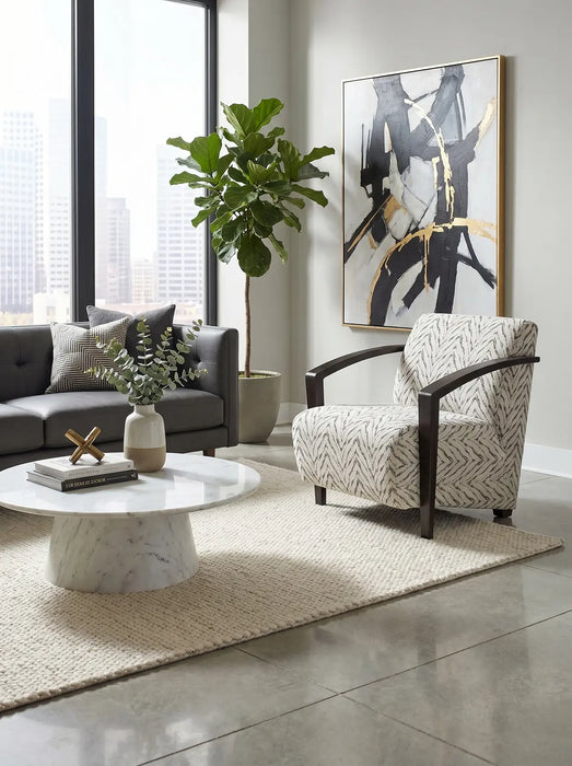 Modern living room with large windows, a gray sofa, patterned armchair, marble coffee table, potted plant, abstract wall art, and a neutral rug on a polished floor. The space is elevated by the Falcon Accent Chair, which adds both comfort and style.