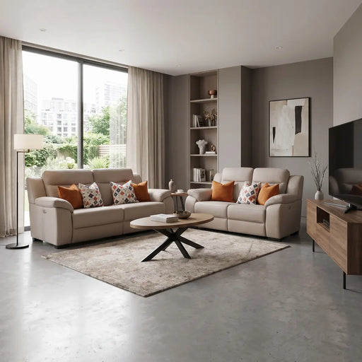 Contemporary living room featuring a Lorenzo Electric Recliner 3 seater sofa in washable fabric, paired with a beige two-seater, patterned and orange cushions, a round coffee table on a rug, floor lamp, built-in shelves, wall art, TV on a wooden stand, large window with curtains, and greenery outside.