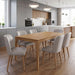 Modern kitchen with grey cabinets, wood accents, and a wooden dining table surrounded by six Mia Dining Chairs featuring taupe leather upholstery and solid oak legs on wooden floors under two round pendant lights.
