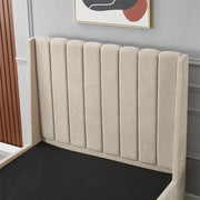 The Oscar Bedframe, a contemporary upholstered bed with a high, vertically tufted wingback design, is showcased in a minimal bedroom. A gray wall with decorative molding and an abstract artwork above the headboard complete the look.