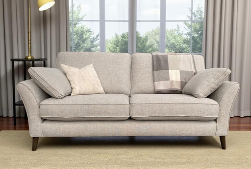 The Retro sofa features light gray Aquaclean fabric, beech frames, two cushions, and a plaid blanket on a beige rug. A floor lamp stands left of the sofa by large windows with gray curtains revealing green trees. Made to order.