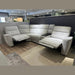 The Avery Electric Recliner Corner is a modern light gray L-shaped sectional sofa featuring two recliner seats, perfect as a contemporary living room centerpiece, shown here in a showroom with wooden and tile flooring.