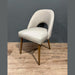 The Florence Dining Chair showcases light gray upholstery, a curved backrest, and wooden legs, set on a light wood floor with a gray wall background.