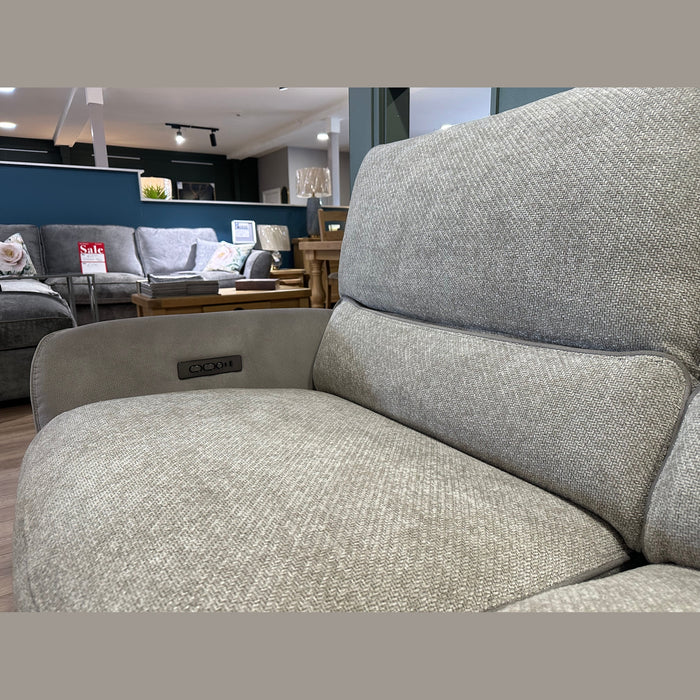 Close-up of a light gray easy-clean fabric sofa armchair in a furniture store. Other sofas, tables, and decor items are visible in the background, including the Willow Corner sofa. A Sale sign can be seen on the left side.