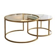 The Salzburg Nest features two round modern coffee tables with gold metal frames; the larger table comes with a glass top, while the smaller table showcases a white marble top. Both tables are displayed against a plain white background.