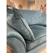 A close-up of the plush, teal Savoy Armchair with a large matching cushion in a cozy, well-lit living room. Decorative accents and pampas grass in the background showcase quality Irish-made furniture.