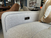 Close-up of the armrest on the light gray Lennox Electric Recliner Sofa, featuring built-in USB ports, displayed in a modern furniture showroom with other seating and decor in the background.