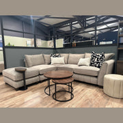 A light gray Zoey Chaise Corner sofa with patterned throw pillows, paired with two round nesting coffee tables and a small side table on a wooden floor.