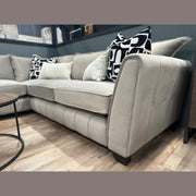 Light gray Zoey Chaise Corner sofa with tufted sides and several decorative pillows in black, white, and neutral tones.