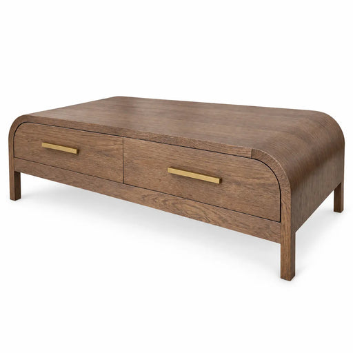The Sienna Coffee Table is a modern rectangular wooden coffee table featuring rounded edges, two drawers with elegant gold handles, and short straight legs.