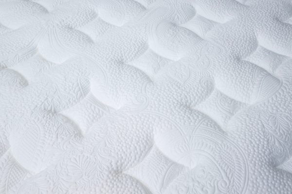 Close-up of the Respa Serene Gel Mattress surface, showcasing a white, quilted texture with intricate, raised designs and gentle, curved indentations—expertly crafted with moisture-wicking materials to help keep you cool and comfortable all night long.