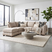 Beige Zoey Chaise Corner sofa with a chaise lounge, accented with patterned throw pillows and a throw blanket, surrounding a round concrete coffee table on a textured area rug.