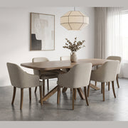 The Ashton Dining Table is a solid ash wood dining table with an architectural X-shaped base, surrounded by six upholstered armchairs with wooden legs.