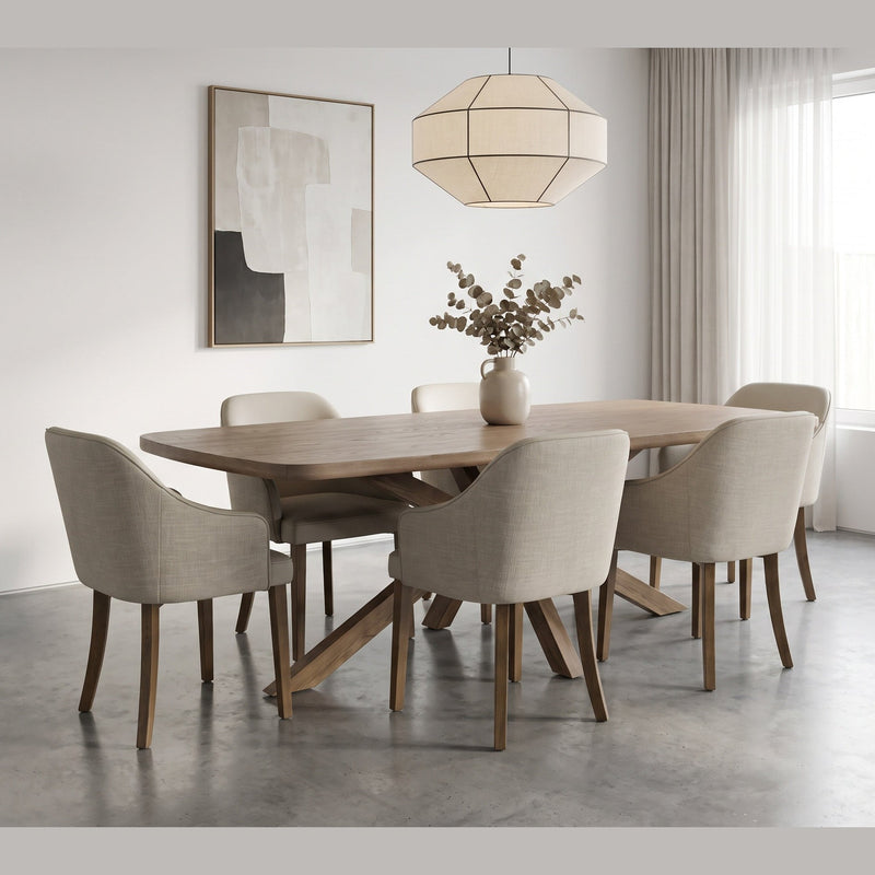 The Ashton Dining Table is a solid ash wood dining table with an architectural X-shaped base, surrounded by six upholstered armchairs with wooden legs.