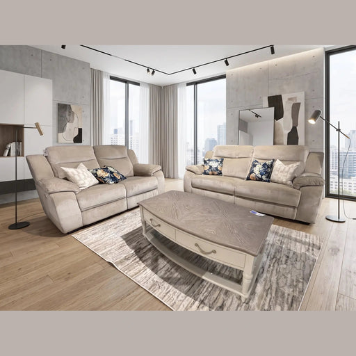 Modern living room featuring a contemporary sofa and two Lorenzo Electric Recliner Sofas in beige, accented with floral cushions, a wooden coffee table on a rug, floor lamps, large windows offering city views, and abstract art displayed on concrete walls.