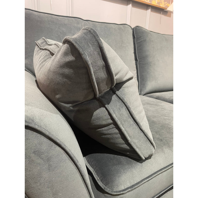 A close-up of a gray, made-to-order Retro Sofa Range shows a large matching cushion angled on the armrest. The plush velvet fabric highlights visible seam details on both the cushion and armrest.