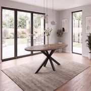 Elson Oval Table with a black metal base, centered in a room with a large area rug and glass patio doors.