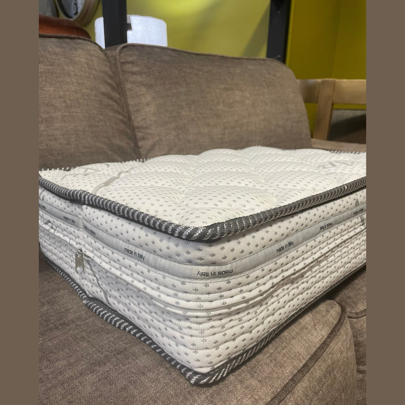A thick, white and gray pocket sprung mattress topper with quilted stitching and "made in Italy" on the side sits on the Sqaured Sofabed, a brown upholstered sofa bed.