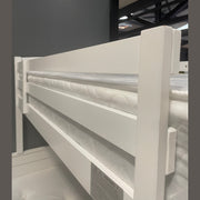 A close-up of the Karol Bunkbeds, featuring a white frame and top mattress, set against a gray wall in a brightly lit showroom—ideal for anyone looking for stylish children's beds or versatile bunk bed solutions.