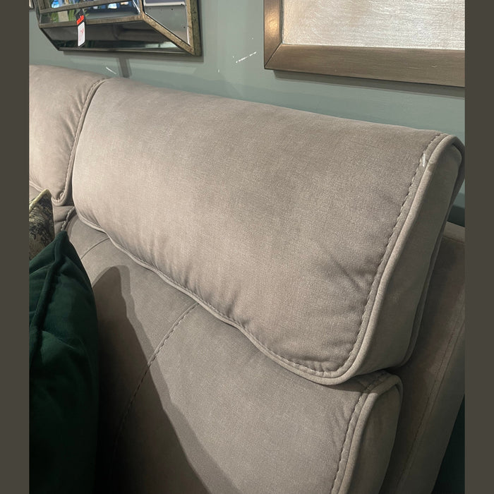 A close-up of the Sheldon Electric Recliner with light gray, washable upholstery and a cushioned headrest is placed beneath a framed mirror on a green wall. A dark green pillow is partly visible on the left side.