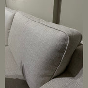A close-up of the Alice Corner Group in light gray aqua clean fabric, featuring plush back cushions and set against a plain beige wall. Partially visible in the upper left is a framed mirror on the wall.