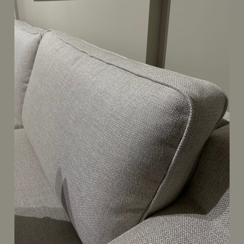 A close-up of the Alice Corner Group in light gray aqua clean fabric, featuring plush back cushions and set against a plain beige wall. Partially visible in the upper left is a framed mirror on the wall.