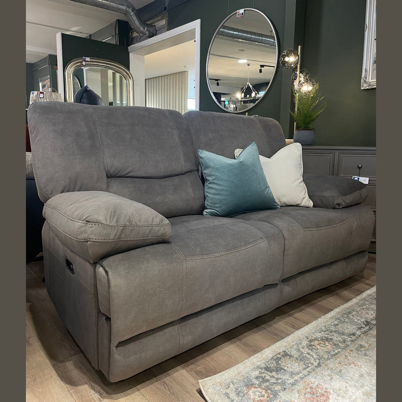 A Gibson Electric Recliner in gray washable fabric with two blue-green and one beige throw pillows rests on a wooden floor in a modern living room featuring green walls, mirrors, and decorative plants.
