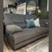 A Gibson Electric Recliner in gray washable fabric with two blue-green and one beige throw pillows rests on a wooden floor in a modern living room featuring green walls, mirrors, and decorative plants.
