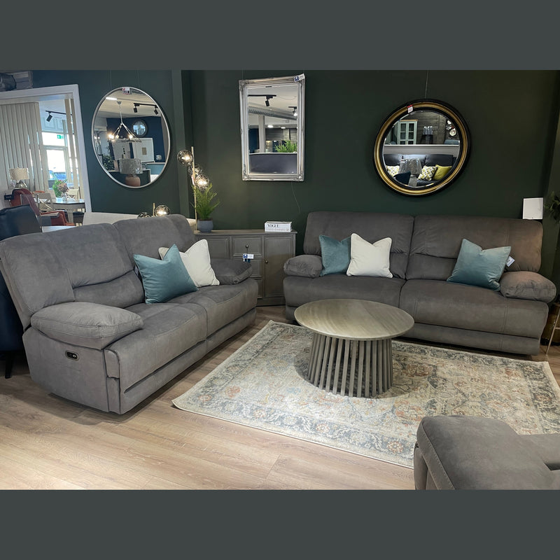 A cozy living room features the Gibson Electric Recliner in gray washable fabric, paired with a matching 3-seater sofa, round wooden coffee table, and patterned rug. Decorative pillows and wall mirrors add a modern touch.