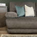 A close-up of the Gibson Electric Recliner in brown suede, styled as a 3-seater with a teal velvet pillow, a cream pillow, and a gray side table. A patterned rug appears on the wooden floor in the foreground.