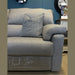 The Hemingway recliner sofa, in light gray aqua clean fabric with a matching cushion, is shown in a showroom. "Cloud Zero, Zero Gravity. Maximum Comfort" is printed on the seat. A white table and clock are in the background.
