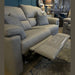 The Hemingway is a light gray recliner sofa with Aqua Clean fabric and an extended footrest, shown in a showroom featuring decorative clocks, lamps, a blue accent wall, and another sofa in the background.