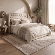 Ambassador Storage Bedframe featuring an upholstered chenille frame with a tufted headboard and wingback sides, made up with layered neutral bedding.