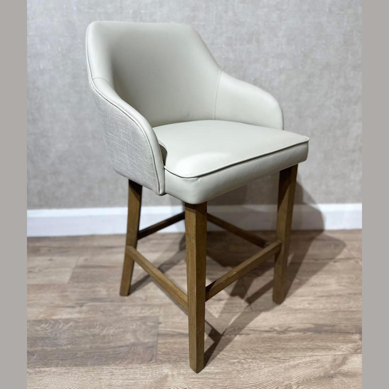 The Como Counter Stool showcases a light beige cushioned leatherette seat and backrest, wooden legs, and footrest—delivering a sleek, modern look perfect for any space.