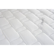 Close-up of the King Koil Extended Life Plus mattress shows its soft, textured surface with a rectangular quilted pattern, giving a padded and comfortable appearance. Faint writing can be seen on the right side.