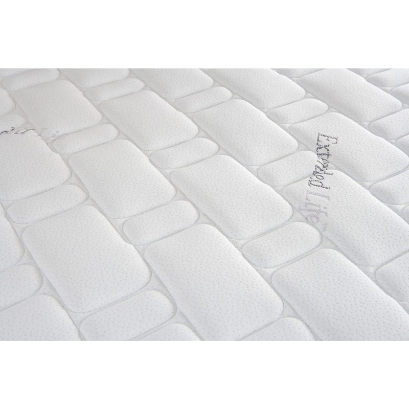 Close-up of the King Koil Extended Life Plus mattress shows its soft, textured surface with a rectangular quilted pattern, giving a padded and comfortable appearance. Faint writing can be seen on the right side.