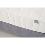 Close-up of a white, quilted King Koil Spinal Guard (ICA) mattress with a textured pattern for posture support on a gray base. A small fabric tag on the mattress reads HANDMADE. Brand: vendor-unknown.
