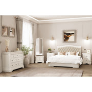 A modern bedroom with neutral tones from the Mabel Bedside, featuring a taupe bed frame, two white nightstands, matching dressers, a tall mirror, wall art, curtains, and decorative plants on a light wood floor with a beige rug.