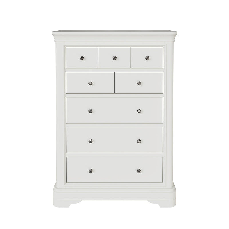 The Mabel Tall Chest by vendor-unknown is a white wooden dresser with seven drawers of various sizes, each with a round silver knob and small curved feet—a chic addition to the Mabel Bedroom Collection.